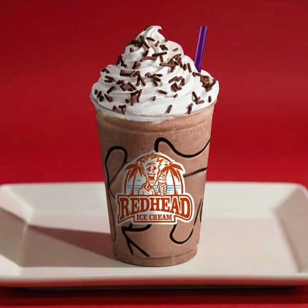 Redhead Ice Cream chocolate milkshake with whipped cream, chocolate sprinkles, and a purple straw.