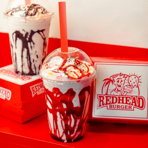 Two RedHead Burger milkshakes, one with chocolate and one with strawberry drizzle and sprinkles.