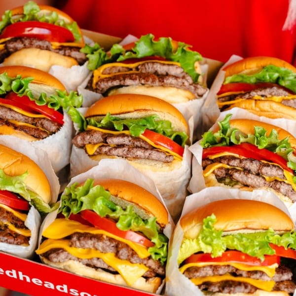 A dozen RedHead Burger double cheeseburgers with lettuce and tomato, individually wrapped in a red box.