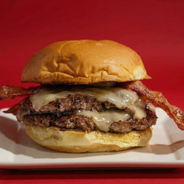 Double patty RedHead Burger with melted cheese and crispy bacon on a white plate.